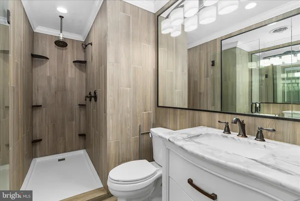 a bathroom with a granite countertop sink toilet a mirror a vanity and shower