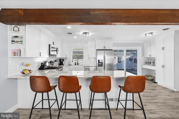 a kitchen with stainless steel appliances granite countertop a table chairs and a refrigerator