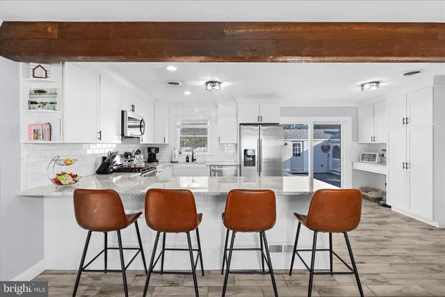 a kitchen with stainless steel appliances granite countertop a table chairs and a refrigerator