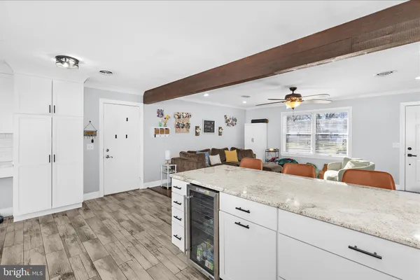 a hall with kitchen island white cabinets and wooden floor