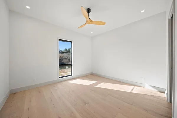 a view of an empty room with wooden floor and windows