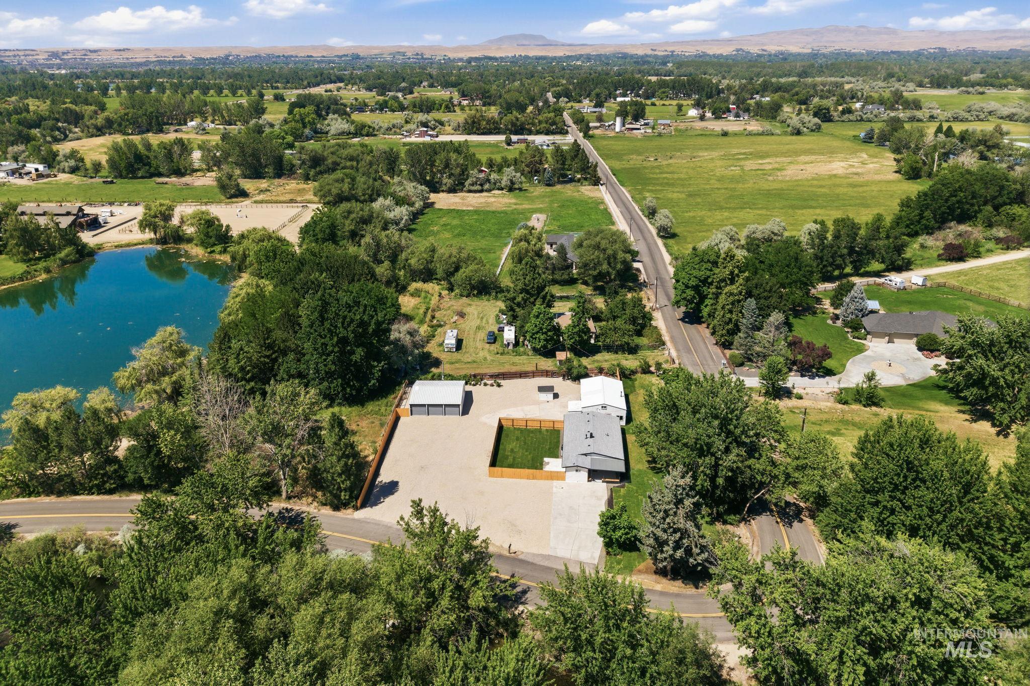 2152 Artesian Road Eagle, ID 83616 - Photo 6 of 50 Expansive property featuring a gravel lot, a detached multi-bay garage, a separate building with a light-colored roof, and a fenced green area