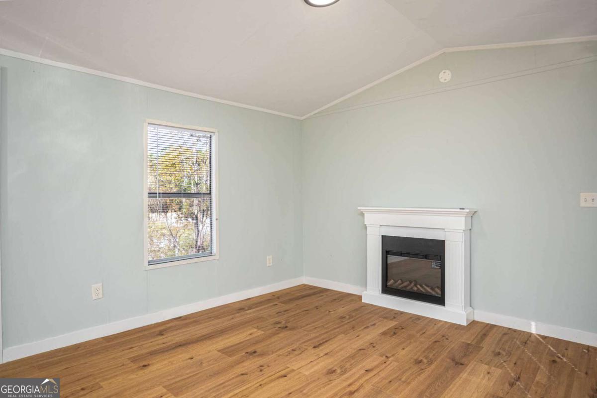 139 Anglin Road Jefferson, GA 30549 - Photo 11 of 26 an empty room with wooden floor a fireplace and windows