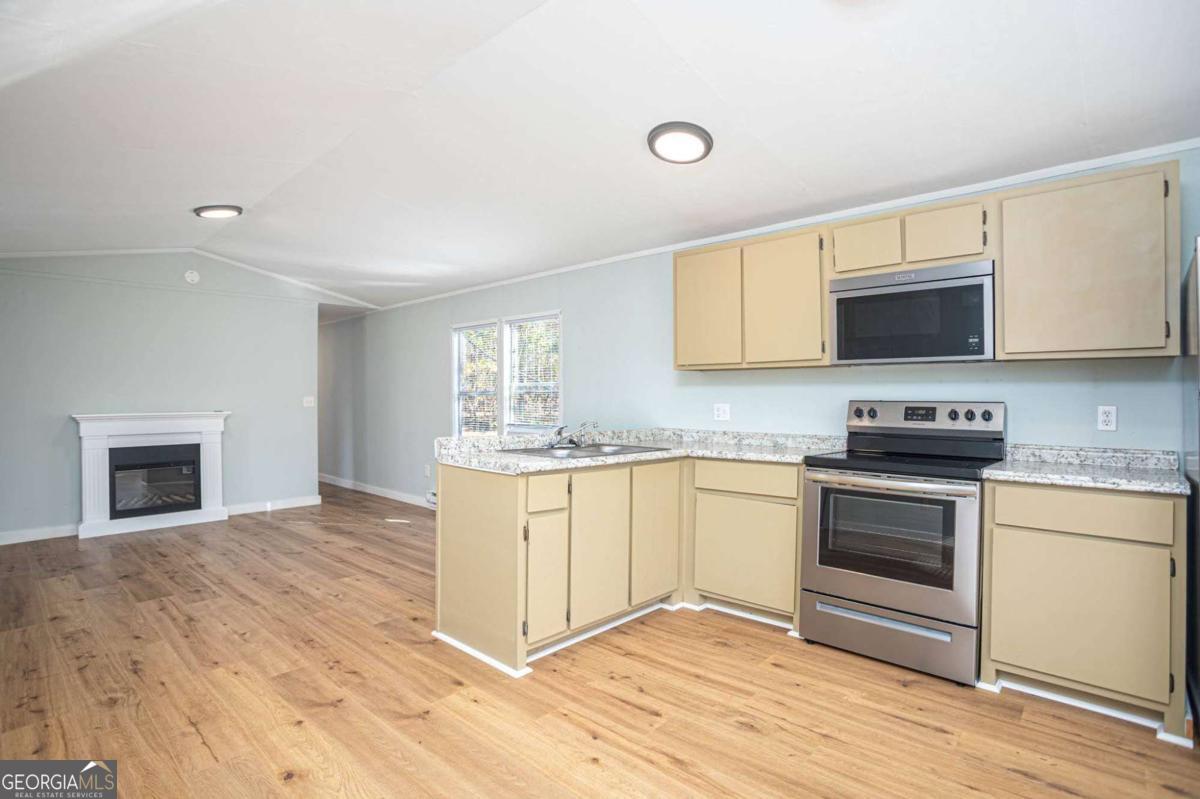139 Anglin Road Jefferson, GA 30549 - Photo 7 of 26 a kitchen with granite countertop a stove a sink and a microwave