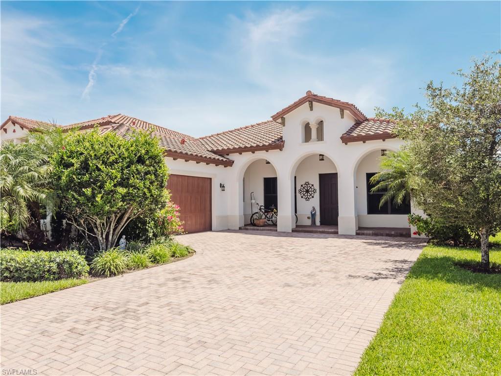 Mediterranean / spanish home with a tiled roof, an attached garage, stucco siding, and decorative driveway