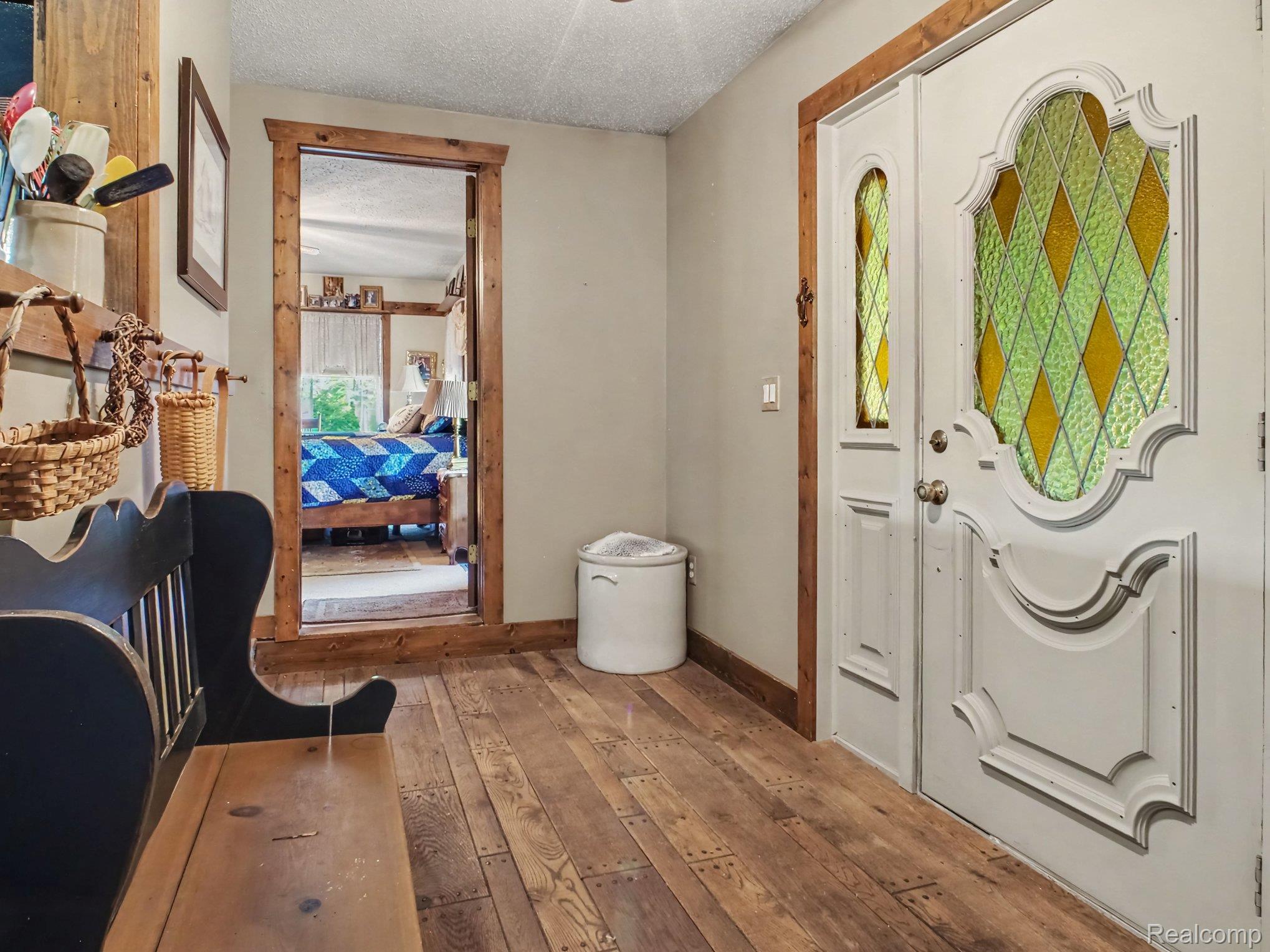 3284 Pratt Road Metamora, MI 48455 - Photo 3 of 22 Entryway featuring wood-finish flooring, a white front door with decorative stained glass, and natural wood trim around doorways