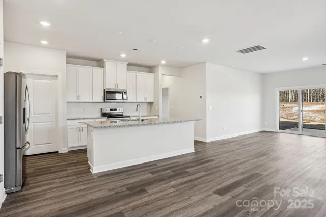 a kitchen with wooden floors white cabinets and refrigerator