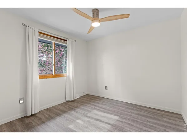 an empty room with wooden floor cabinet and windows