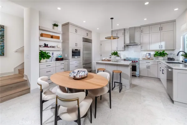 a kitchen with stainless steel appliances kitchen island granite countertop a dining table chairs and white cabinets