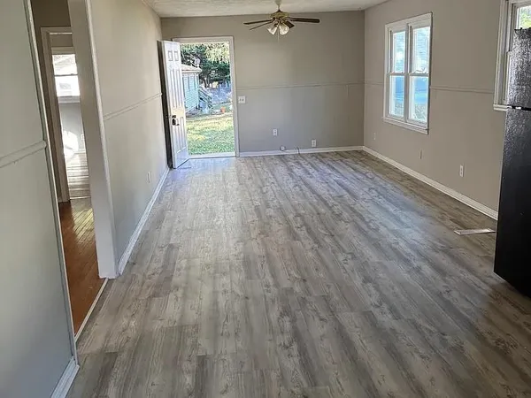a view of an empty room with wooden floor and a window