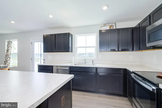 a kitchen with stainless steel appliances a table chairs refrigerator and wooden cabinets