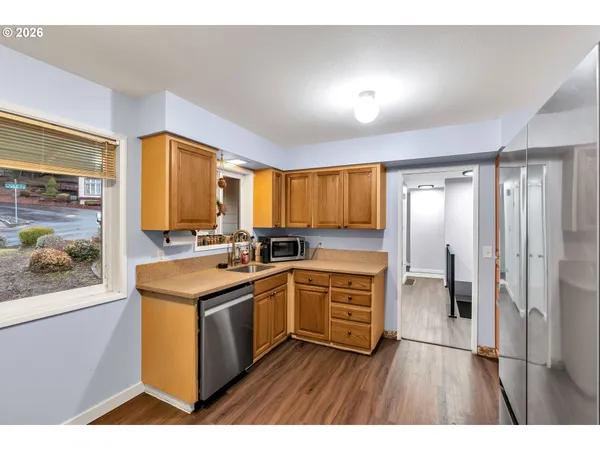 a kitchen with stainless steel appliances granite countertop a stove a sink and a refrigerator with wooden floor
