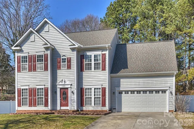 a view of a white house with large windows next to a yard