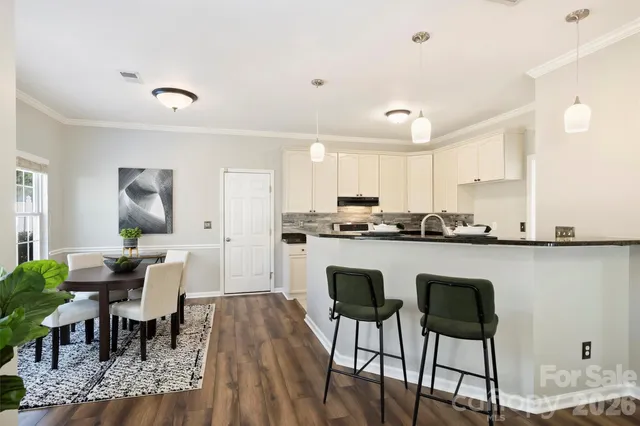 a kitchen with a refrigerator a stove a dining table and chairs with wooden floor