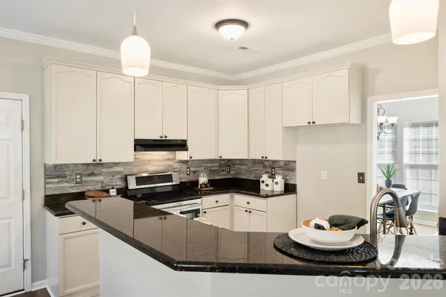 a kitchen with granite countertop a sink and white cabinets