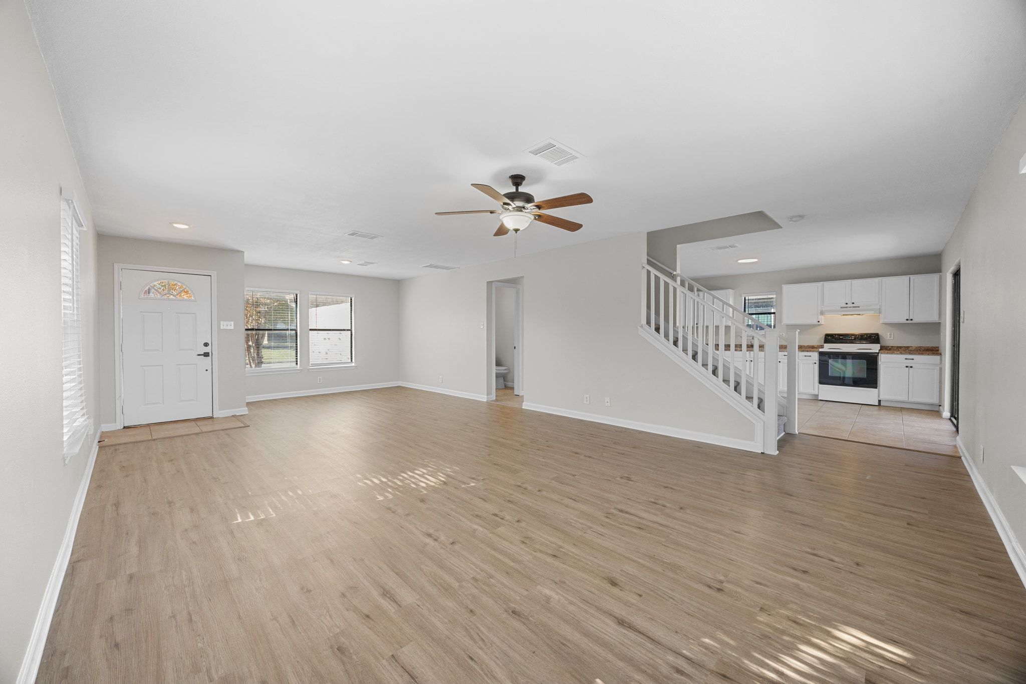 Unfurnished living room with stairs, light wood finished floors, recessed lighting, and a ceiling fan