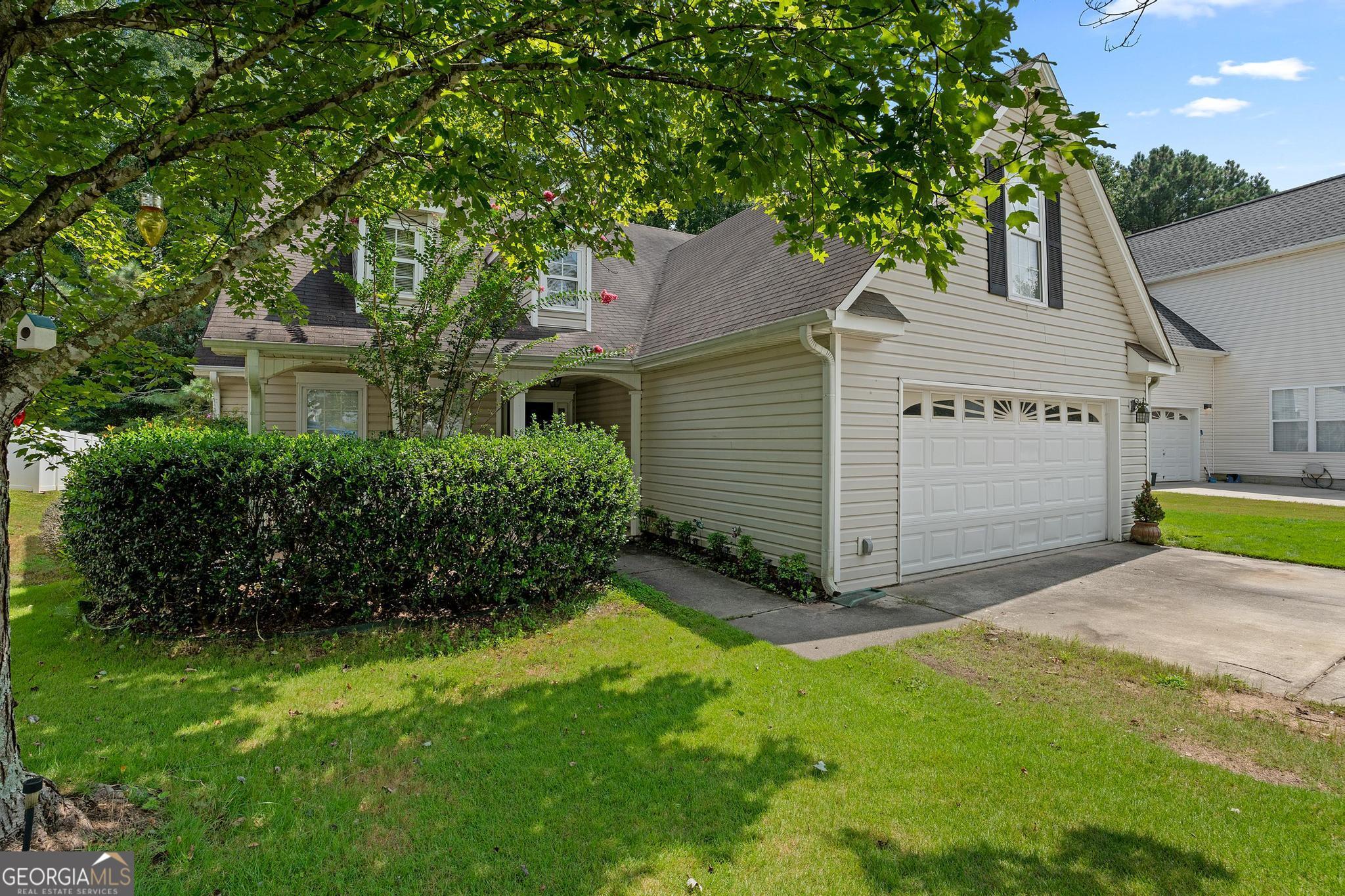 a view of a house with a yard plants and large tree
