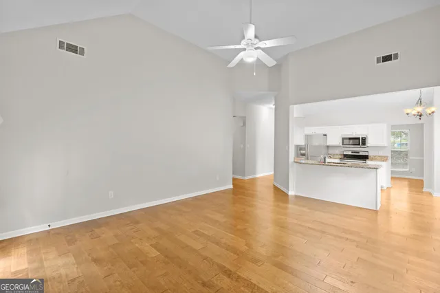 a view of an empty room with wooden floor fireplace and a window