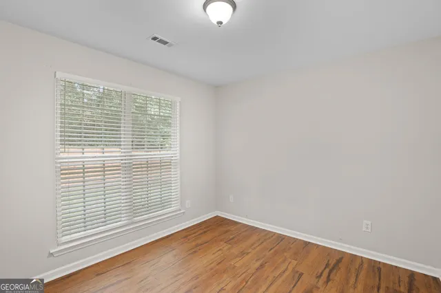 a view of an empty room with a window and wooden floor