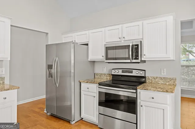a kitchen with stainless steel appliances white cabinets a stove a microwave and a refrigerator