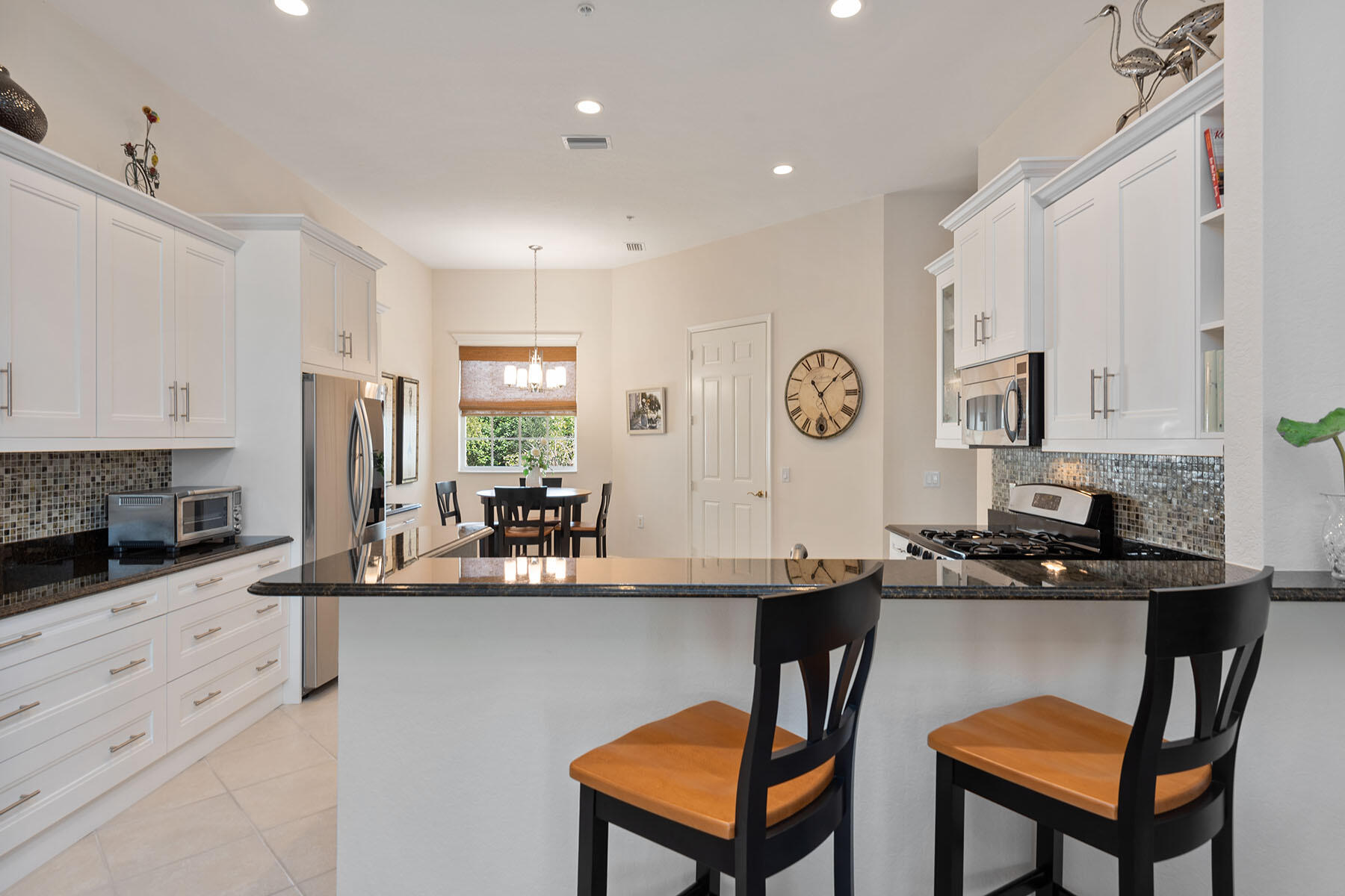 9263 Museo Circle, Unit 202 Naples, FL 34114 - Photo 6 of 45 a kitchen with stainless steel appliances granite countertop a stove a sink a microwave a dining table and chairs