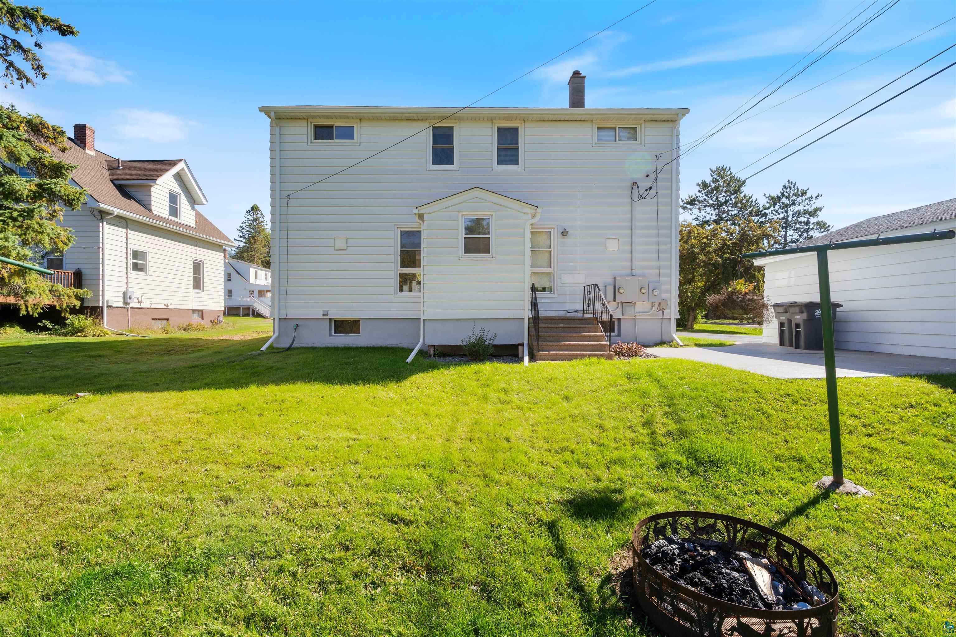 3715 Rendle Avenue Duluth, MN 55803 - Photo 7 of 20 Expansive green lawn with a white-sided two-story structure and an exterior staircase with a landing