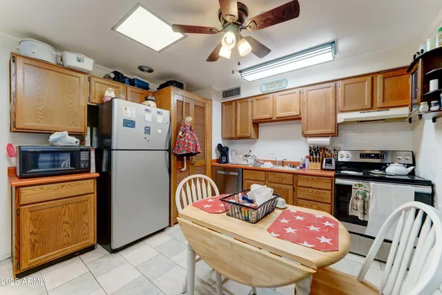 a kitchen with stainless steel appliances granite countertop a refrigerator a sink a stove a dining table and chairs with wooden floor