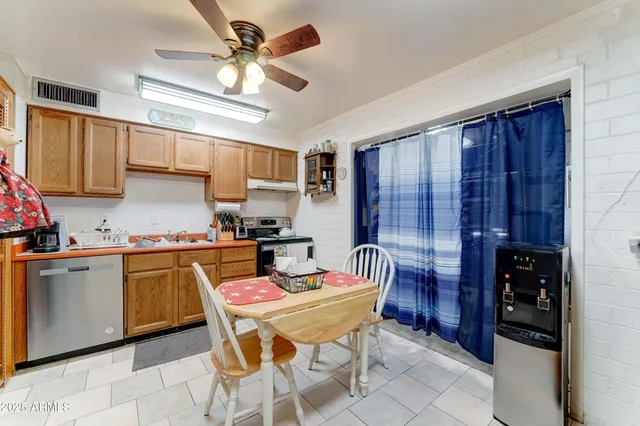 a kitchen with stainless steel appliances granite countertop a sink a stove a dining table and chairs with wooden floor