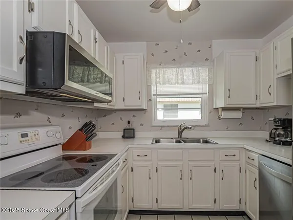 a kitchen with cabinets appliances a sink and a window