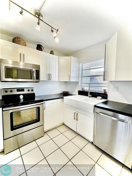 9495 Evergreen Place, Unit 405 Davie, FL 33324 - Photo 2 of 17 a kitchen with stainless steel appliances granite countertop a sink a stove a microwave and cabinets