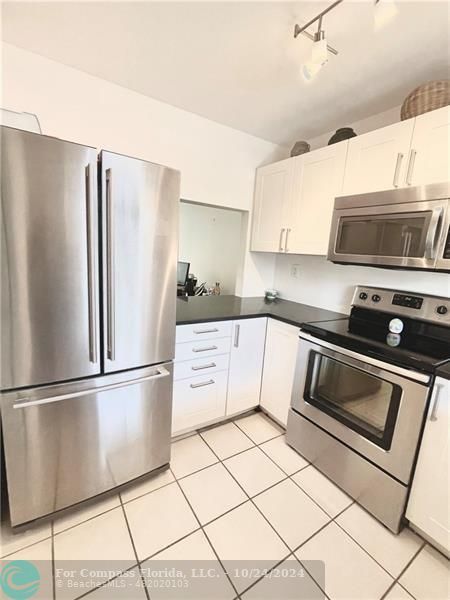 9495 Evergreen Place, Unit 405 Davie, FL 33324 - Photo 3 of 17 a kitchen with stainless steel appliances granite countertop a refrigerator sink and microwave