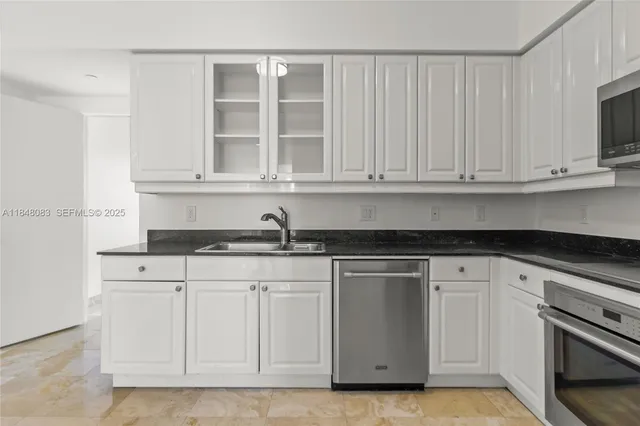 a kitchen with white cabinets and sink