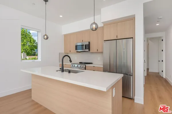 a kitchen with stainless steel appliances granite countertop a refrigerator a sink a stove and a wooden floors