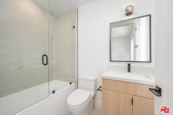 a bathroom with a toilet sink a mirror and shower