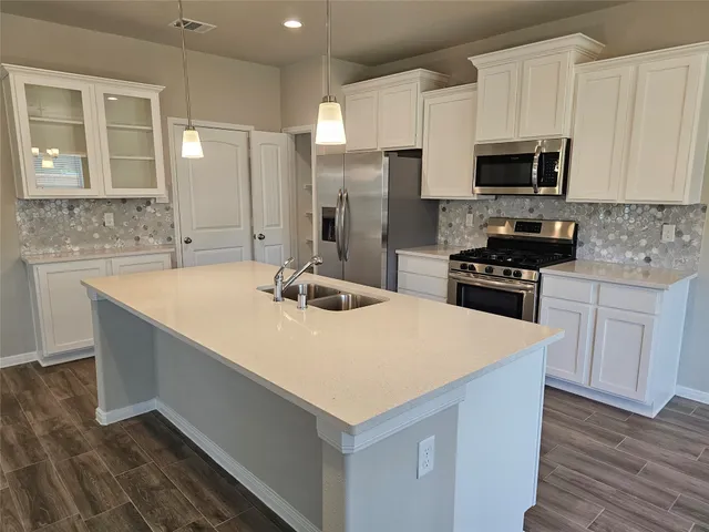 a kitchen with a sink a stove a microwave and white cabinets