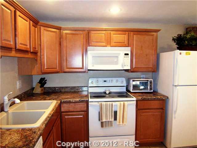 7092 Chippewa Road Colorado Springs, CO 80915 - Photo 3 of 16 Granite Counters, Newer Crisp White Appliances, Medium-Toned Wood Cabinetry