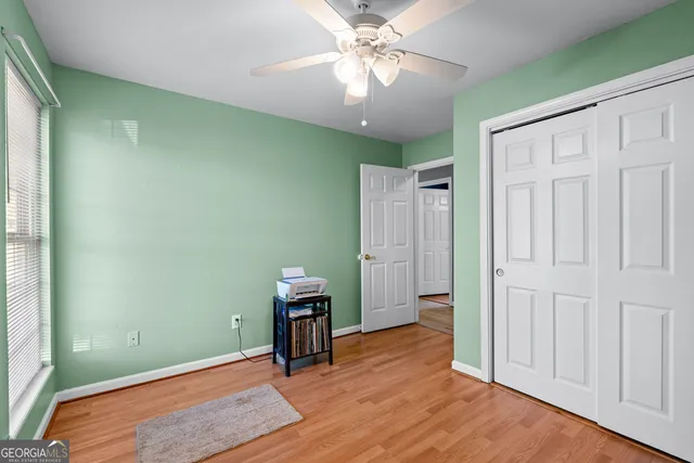 an empty room with wooden floor closet and windows