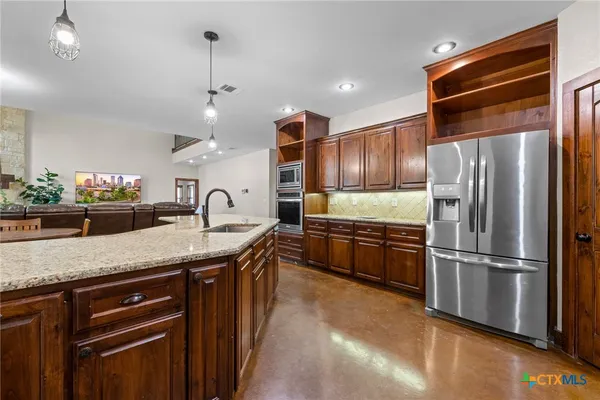 a kitchen with stainless steel appliances granite countertop a stove a sink and a refrigerator