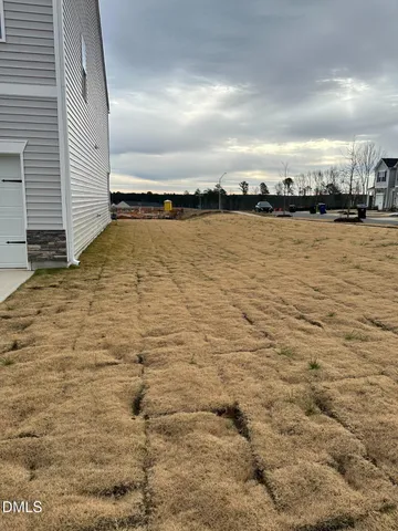 a view of kitchen and empty room with wooden floor