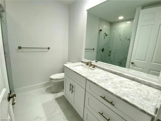 a bathroom with a granite countertop sink a toilet and a mirror