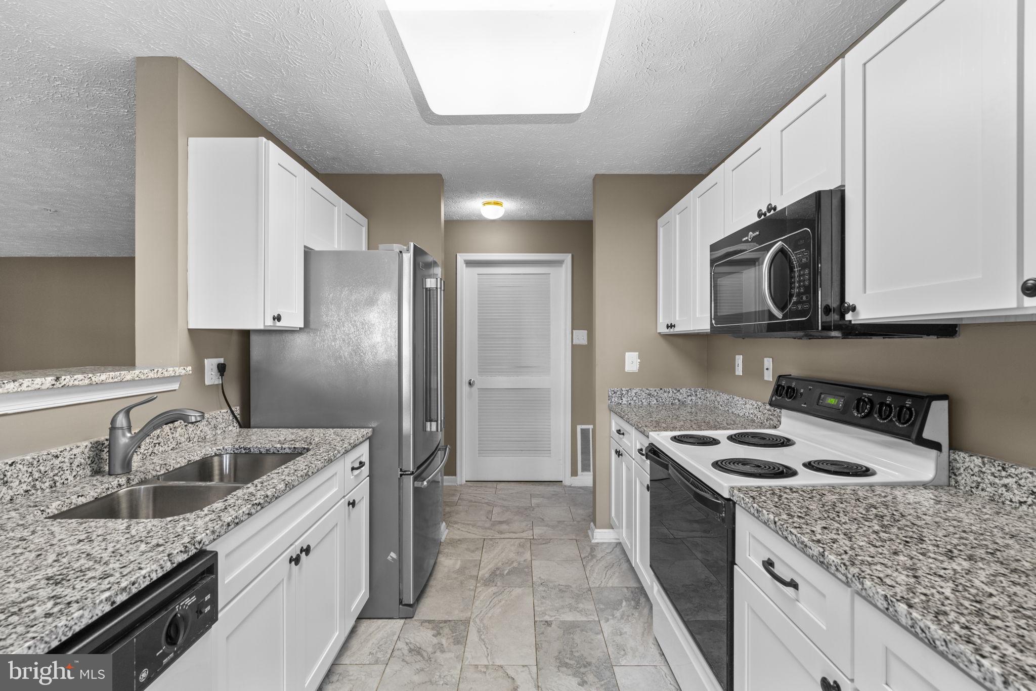 9713 Reese Farm Road, Unit 9713 Owings Mills, MD 21117 - Photo 11 of 30 a kitchen with stainless steel appliances granite countertop a sink stove microwave and refrigerator