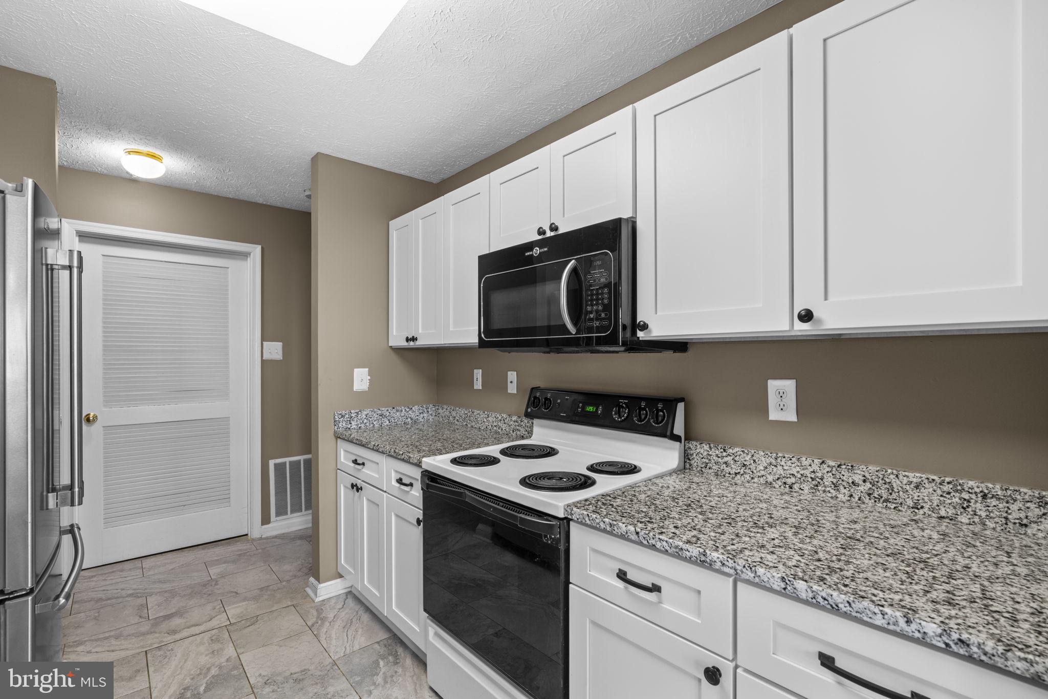 9713 Reese Farm Road, Unit 9713 Owings Mills, MD 21117 - Photo 10 of 30 a kitchen with stainless steel appliances granite countertop white cabinets and a stove