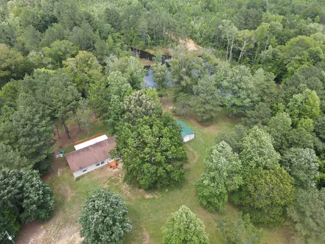 an aerial view of residential house with outdoor space and trees all around