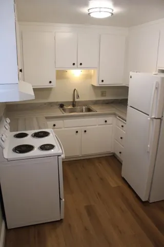 a kitchen with granite countertop white cabinets and white appliances