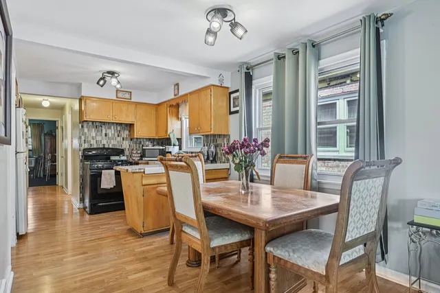 a dining room with wooden floor a chandelier a wooden table and chairs