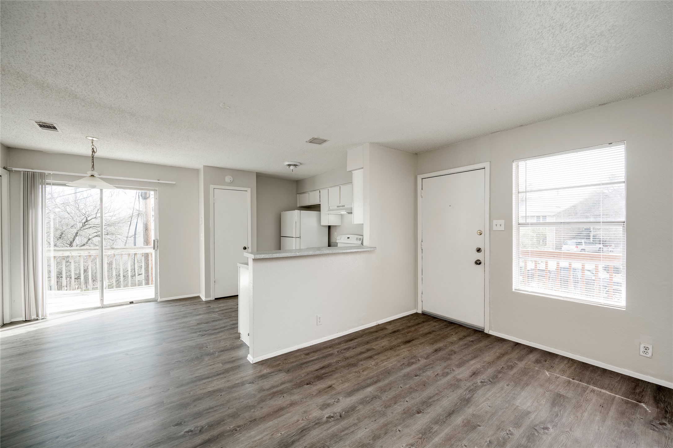 11907 Alpheus Avenue, Unit D Austin, TX 78759 - Photo 5 of 26 a view of a kitchen and an empty room with wooden floor and a window