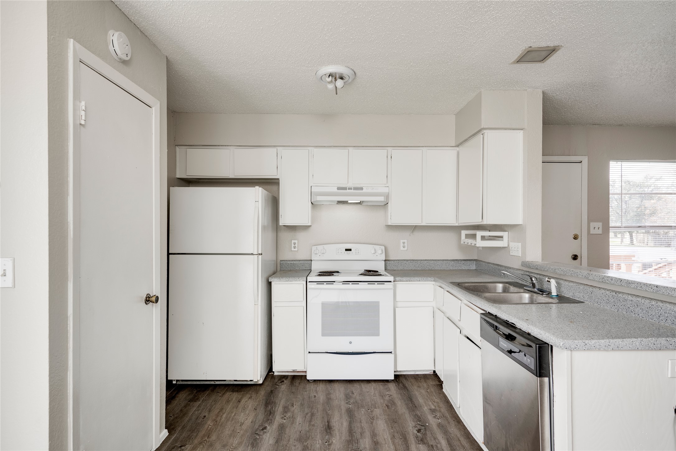 11907 Alpheus Avenue, Unit D Austin, TX 78759 - Photo 7 of 26 a kitchen with a sink a refrigerator a stove and white cabinets