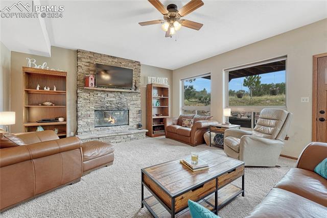 2690 Spaatz Road Monument, CO 80132 - Photo 11 of 50 Carpeted living room featuring ceiling fan, built in features, and a fireplace