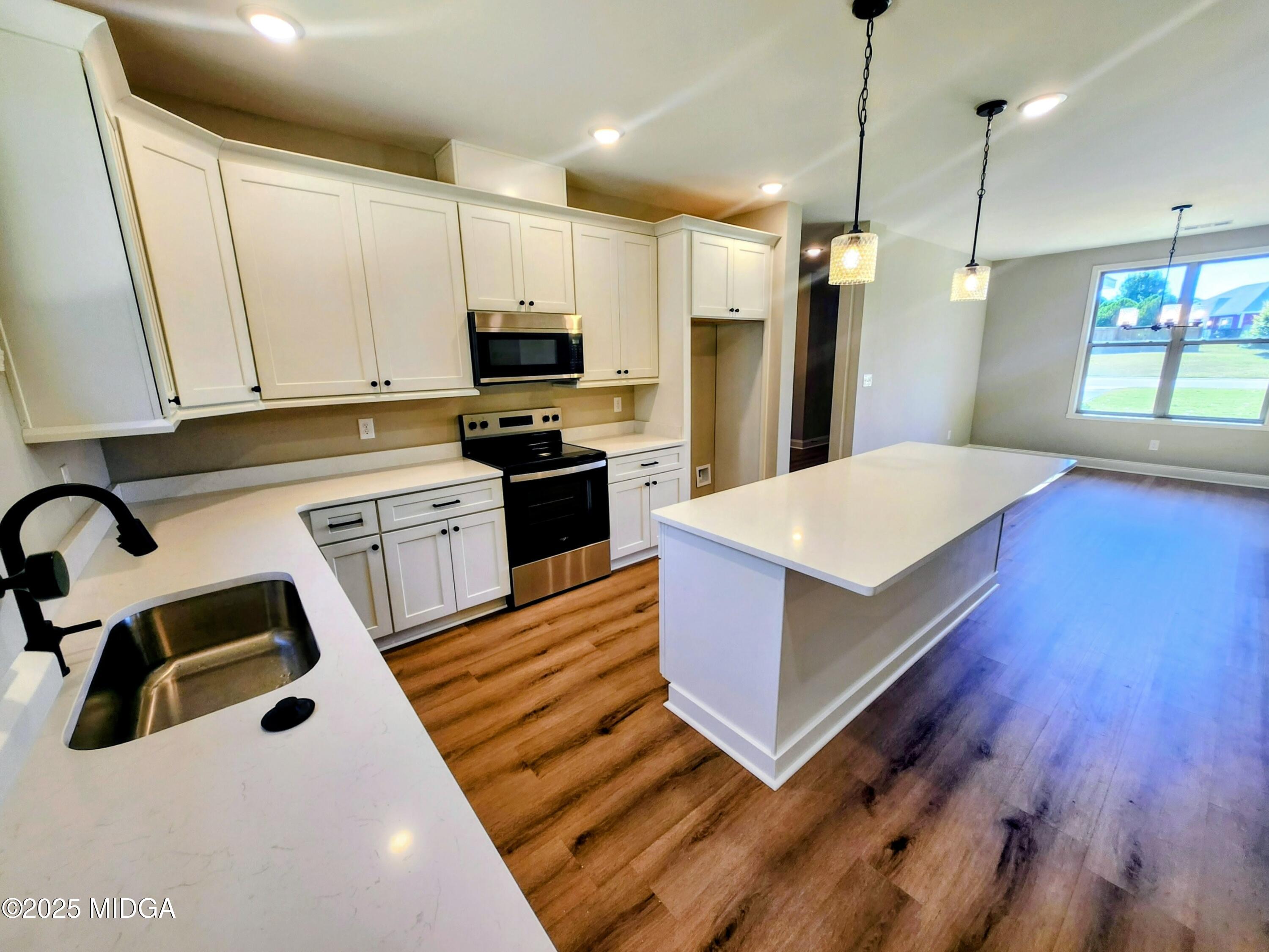 404 Minter Drive Warner Robins, GA 31088 - Photo 24 of 60 a large kitchen with kitchen island a white counter space a sink appliances and cabinets