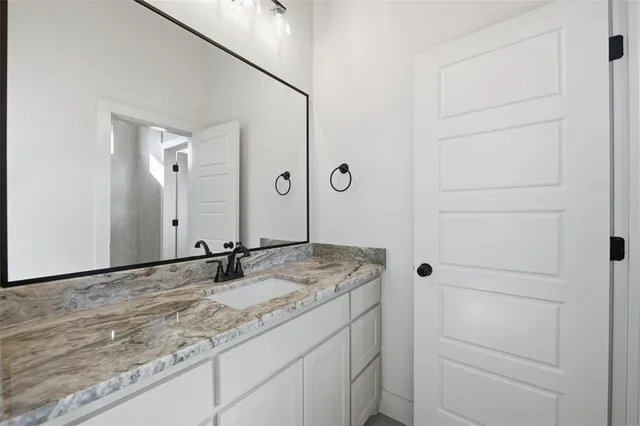 a bathroom with a granite countertop sink and a mirror